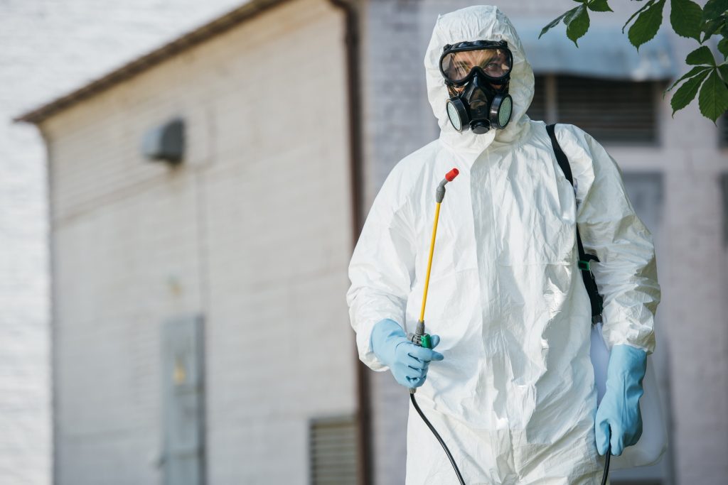 pest control worker in respirator holding sprayer